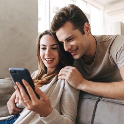 casal jovem com o celular em mãos para usar o simulador de financiamento